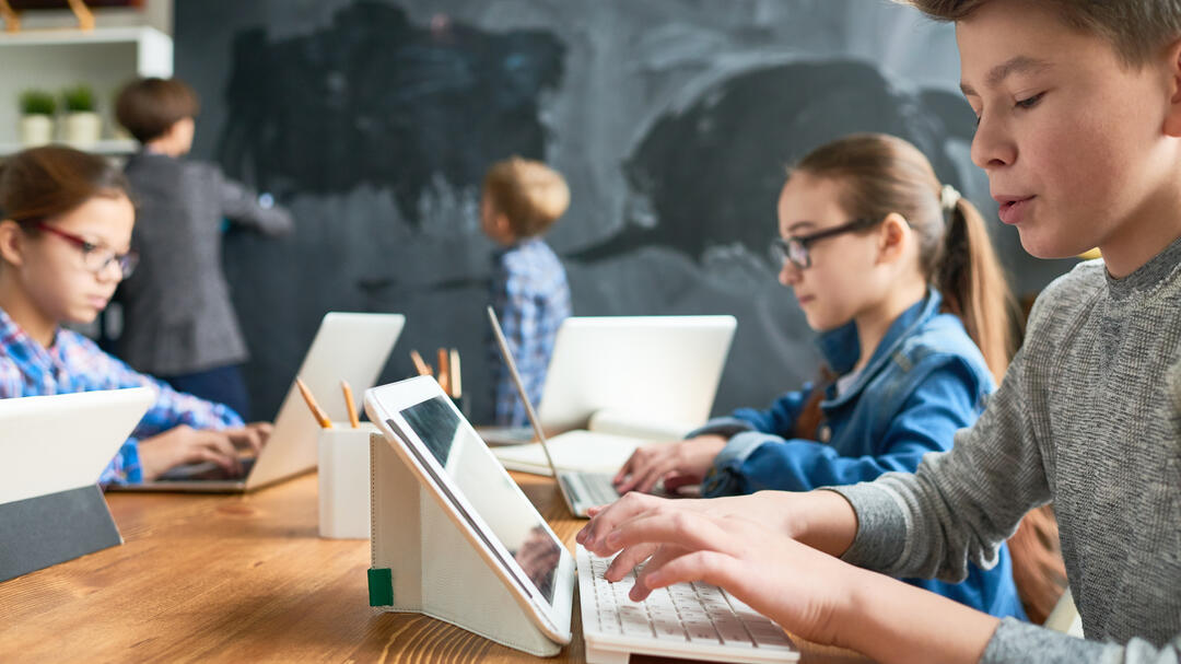 Kinder sitzen im Klassenzimmer vor dem Tablet 
