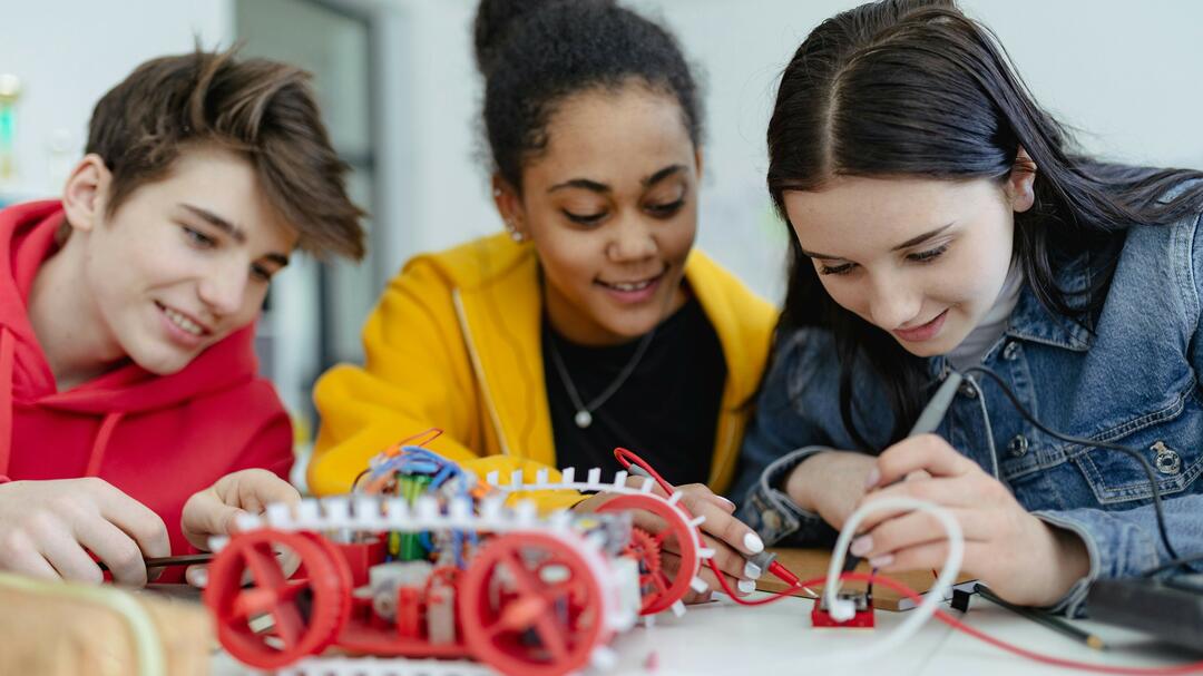 Schülergruppe bauen im Technikunterricht ein Fahrzeug 