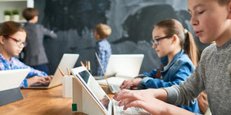 Kinder sitzen im Klassenzimmer vor dem Tablet 