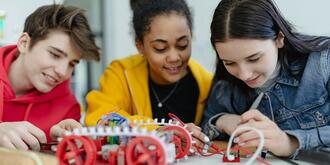 Schülergruppe bauen im Technikunterricht ein Fahrzeug 