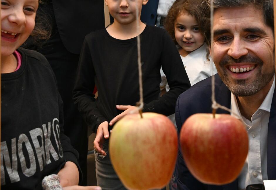 Sven Teuber, Bilcungsminister Rheinland-Pfalz, bei einem MINT-Experiment mit Äpfeln. Mehrere Grunsschulkinder schauen zu